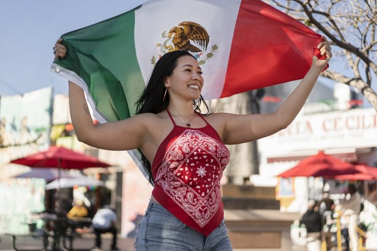 Chicana holding Mexican flag illustrates blog "A Basic Chicano Glossary: 9 Terms You Need To Know"